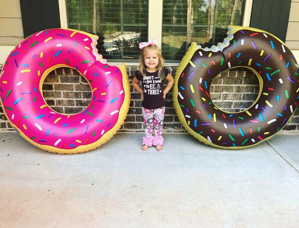 Birthday girls stands between donut inflatables