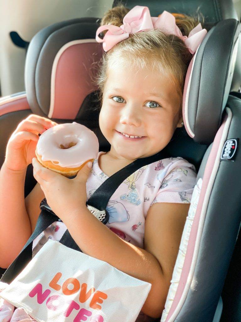 Young girl holding a doughnut, smiling at the camera