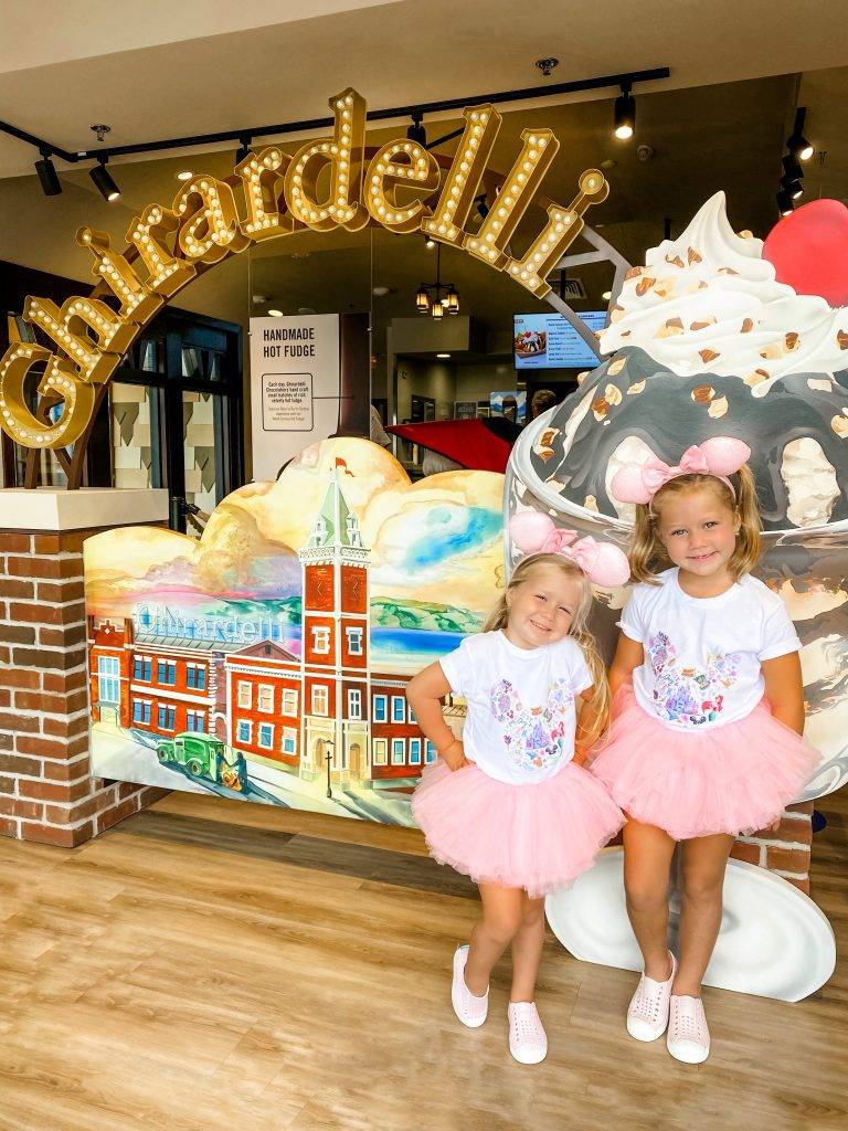 Two girls, wearing pink Minnie Mouse ears, and pink Tutus, smiling 