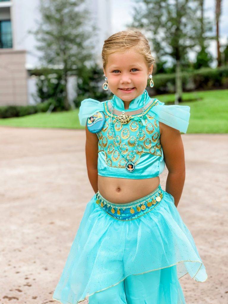 Smiling at the camera is a little girl dressed as Jasmine. 