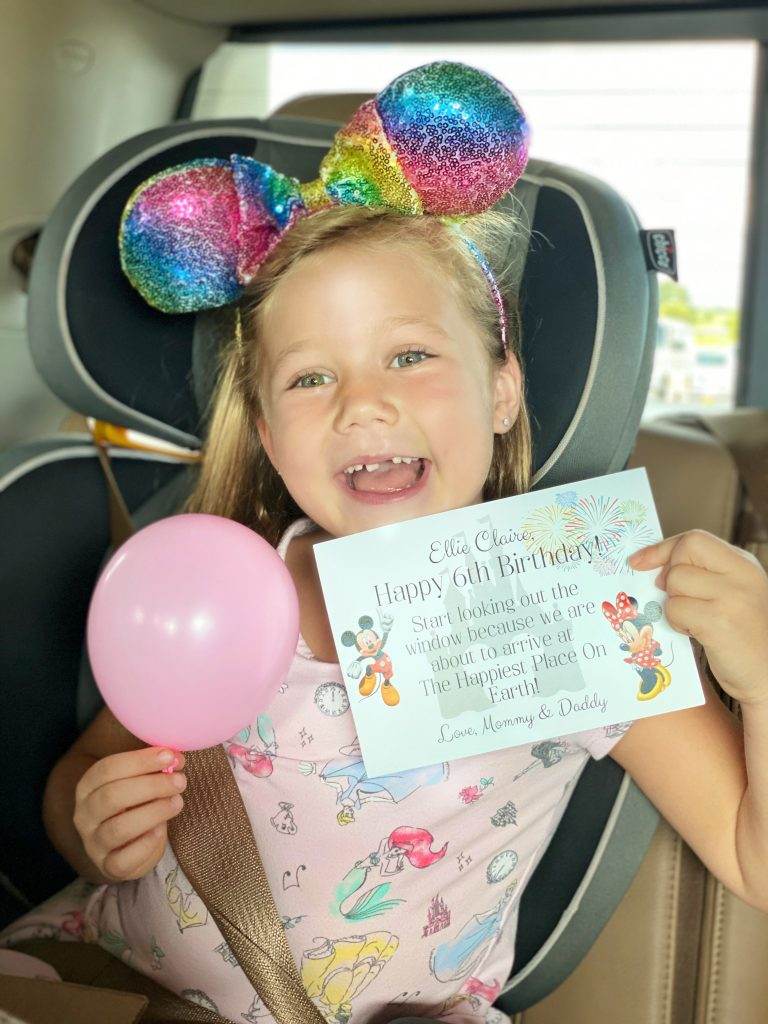 Surprised child holding a note and small balloon sharing a surprise to Disney World.